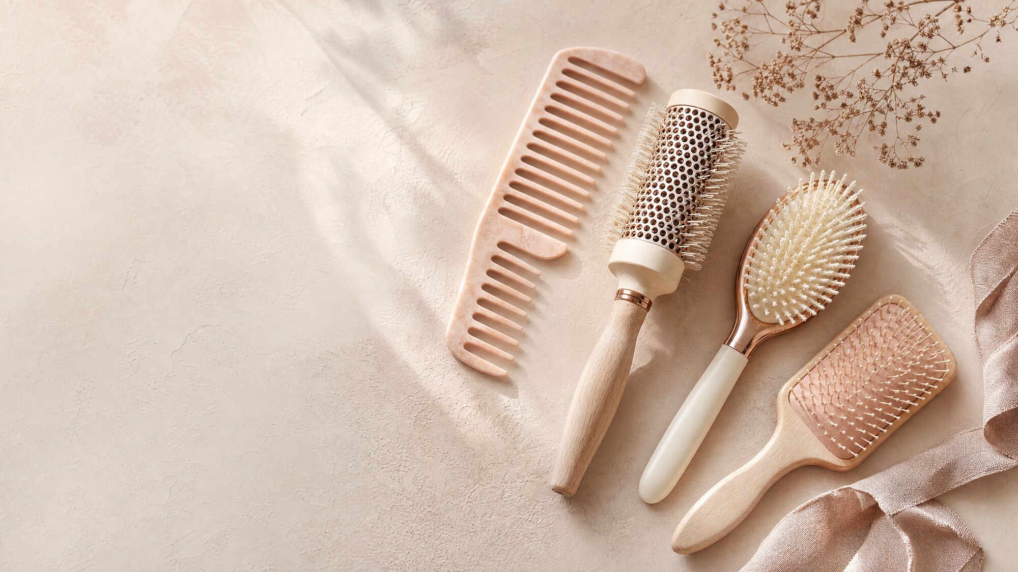An editorial flat lay of combs and brushes on a warm cream surface